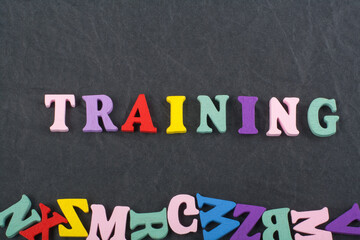 TRAINING word on black board background composed from colorful abc alphabet block wooden letters, copy space for ad text. Learning english concept.