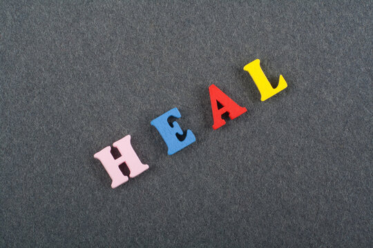 HEAL word on black board background composed from colorful abc alphabet block wooden letters, copy space for ad text. Learning english concept.