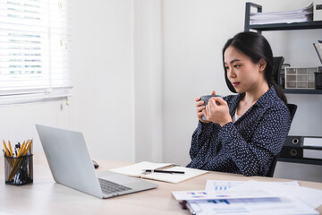 Businesswoman working while enjoying coffee.