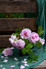 Bouquet of garden pink roses in a vase on a bench in the garden