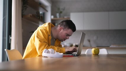 Young man with down syndrome learning online at home, using laptop. Telehealth consultation with doctor.
