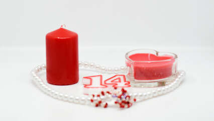 Obraz na płótnie Canvas Valentine's Day is February 14th. Red hearts in all types. Red and pink candles. Background white. Pearl beads and red tinsel.