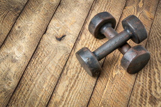 a pair of vintage iron rusty dumbbells on a grained barn wood background, fitness concept