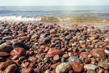 Seashore pebbles with sea and beach in the background. Pebbles and water on the beach in Giruliai, Klaipeda, Lithuania.