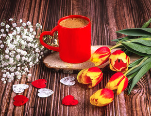 A red cup of coffee with a heart, a bouquet of tulips and gypsophila on a dark wooden background....