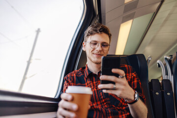 A man is traveling by train and typing messages on the phone.