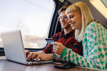 A cheerful young couple commuting by train and ordering online.