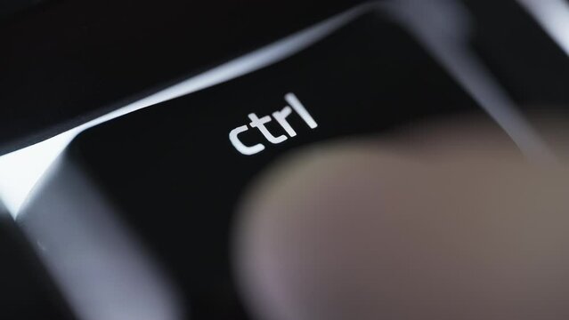 Pressing and holding the CTRL button on black computer keyboard. Close up. 