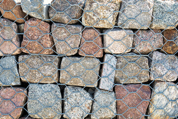 Engineering structure made of stones behind metal wire netting to strengthen the dune bank near sea.