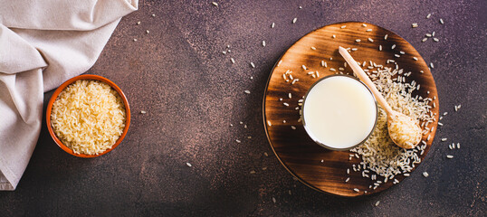 Alternative healthy rice milk in a glass and rice cereal on the table top view web banner