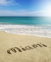 Fototapeta na wymiar Miami text spelled in the sand in South Beach with sunny sky and clear blue ocean water