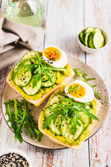 Bruschetta with guacomole, cucumber, egg and arugula on a plate vertical view