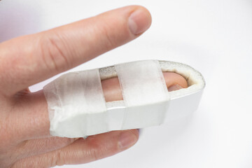 A man's hand with a broken finger and a splint placed on a broken finger on a white background, a broken finger, injury, accident