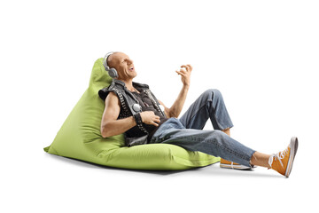 Bald punk man sitting on a green bean bag with headphones