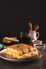 Tiramisu classic dessert with cookies, mascarpone and coffee on a plate on the table vertical view