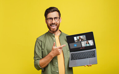 A cheerful man with glasses and a beard excitedly points to a laptop screen displaying