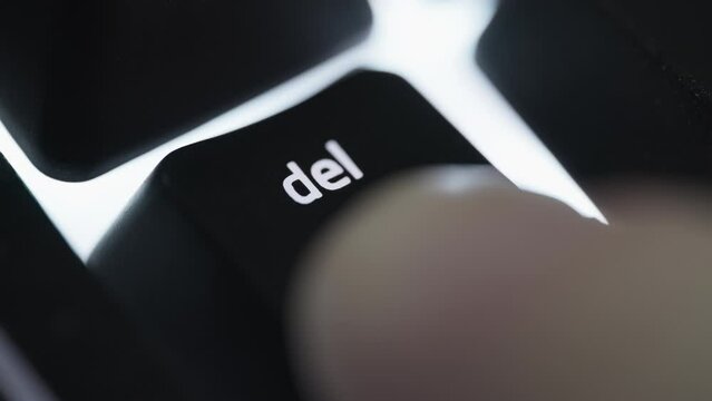 Pressing and holding delete button on black computer keyboard. Close up. 