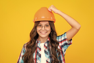 Close up portrait of teenager child builder in helmet. Teenage girl on repairing work isolated on yellow background. - obrazy, fototapety, plakaty