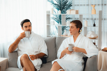Beauty or body treatment spa salon vacation lifestyle concept with couple wearing bathrobe relaxing with drinks in luxurious hotel spa or resort room. Vacation and leisure relaxation. Quiescent - obrazy, fototapety, plakaty