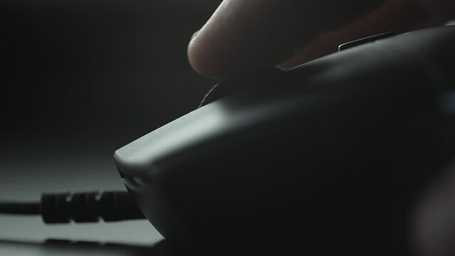 Finger scrolling up with a black mouse wheel. Close up. 
