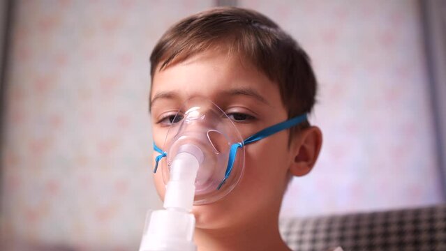 close-up portrait boy is doing nebulizer inhaler treatment. home treatment
