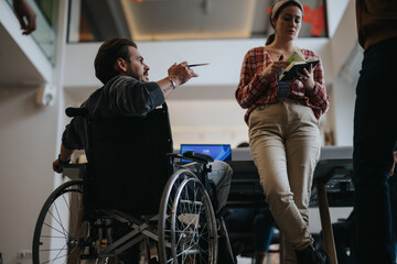 A professional setting with a diverse group, featuring a man in a wheelchair actively participating in a work discussion.