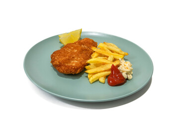 Breaded steak with French fries, with ketchup and mayonnaise, two lemon wedges, served on a turquoise plate. Isolated in a white background.