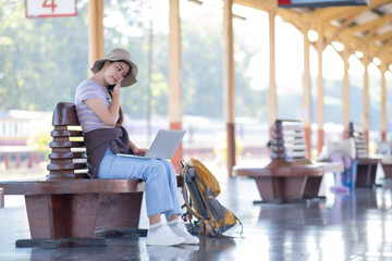 Young Asian woman girl works with a laptop notebook in the train station, Young woman with travel...
