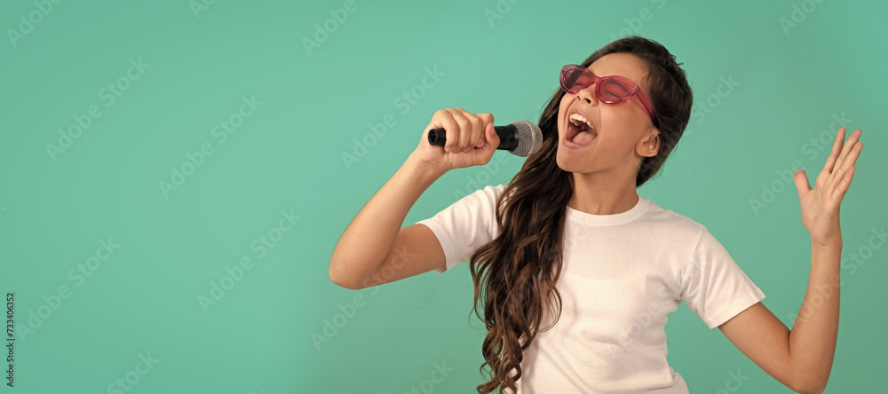 Wall mural Happy kid singer sing karaoke song to microphone blue background, music. Horizontal poster of isolated child face, banner header, copy space.