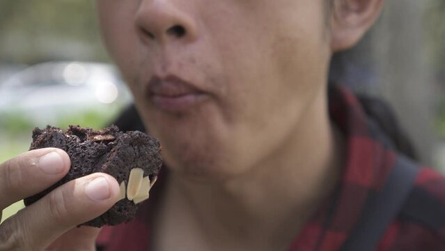 A man is eating brownies topped with almonds. Concept for unhealthy food, fat loss, weight loss, bad diet, diabetes, cholesterol, insulin resistance, and metabolic syndrome.