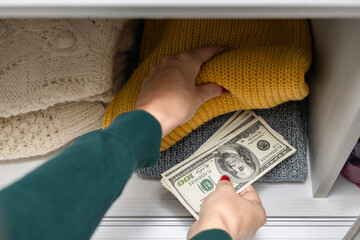 woman hides American dollars in a closet with clothes.