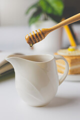Honey dripping from a wooden honey dipper into a Small jug