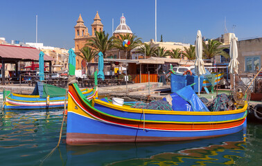 Multi-colored fishing boats luzzi with eyes in the harbor of the village Marsaxlokk on the island Malta.
