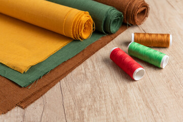 Rolled linen fabric and threads on table - 733417353