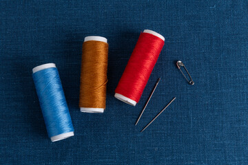 Colorful threads and needles on blue linen fabric - 733417391