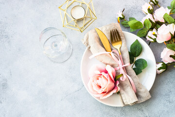 White plate, cutlery and wine glass with pink flowers. Spring table settong. Flat lay with copy...