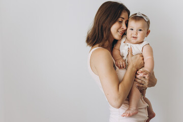 Happy young mother with her adorable baby girl on white background