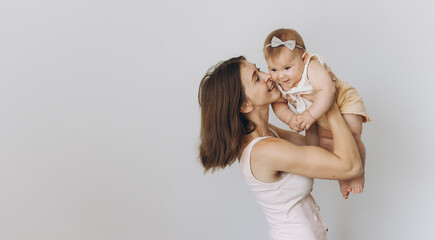 Happy mother with her adorable baby girl while lifting up in the air on white background