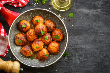 Meatballs in tomato sauce in the skillet at dark table. Flat lay image.
