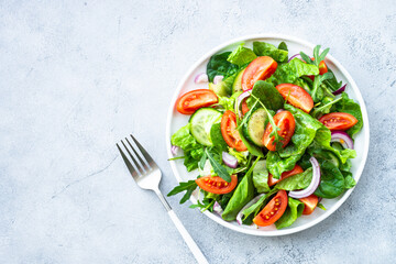 Fresh green salad with leaves and vegetables. Top view with copy space at stone table.