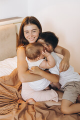 Fototapeta premium Happy young mother spending time with her children in the bedroom