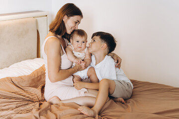 Fototapeta na wymiar Happy young mother spending time with her children in the bedroom