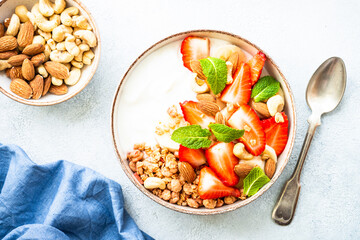 Yogurt with granola and strawberries on white. Healthy snack or breakfast, fruit salad. Top view.