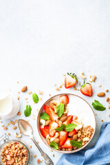 Yogurt with granola and strawberries on white background. Healthy snack or breakfast. Top view with copy space.