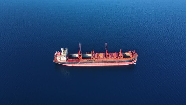 Bulk cargo carrier ship at anchorage washing ship holds before loading in port. Aerial view