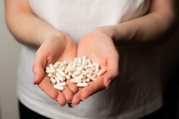 Female hands hold handful of white medicine tabs pills, concept of wellness