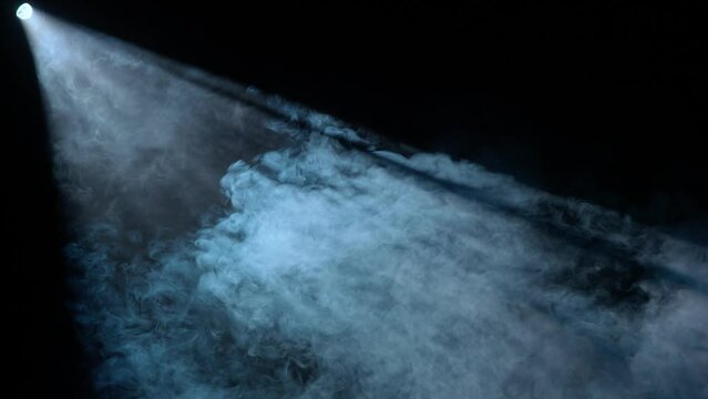 Studio shot of projector haze effect isolated on black background. Blue colored bright rays shining diagonally with smoke.
