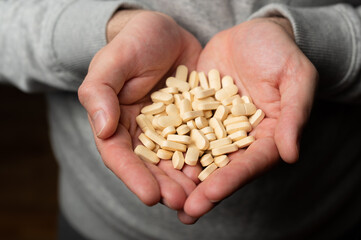 Male hands hold handful of white medicine tabs pills, concept of wellness