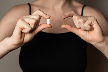 Woman hands hold two pills tabs medicine to kill pain, self help supplements concept, prescribed medicine