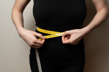 Weight loss measuring concept: woman checks her waist volume size length to make sure she fits the modern standards of beauty